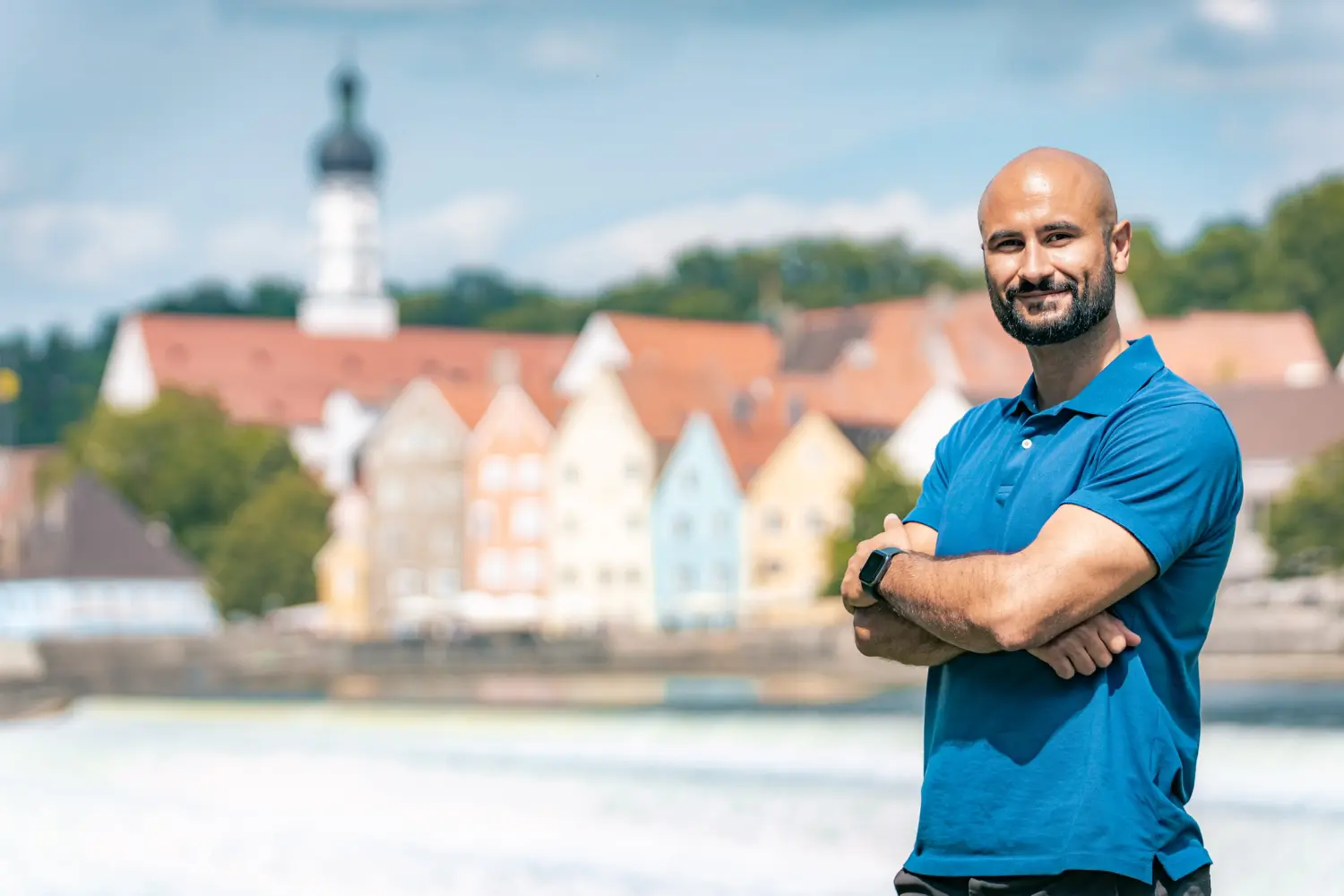 IMMI COP, Sinan Schmeiser vor einem verschwommenen Staatsgebäude im Hintergrund stehend